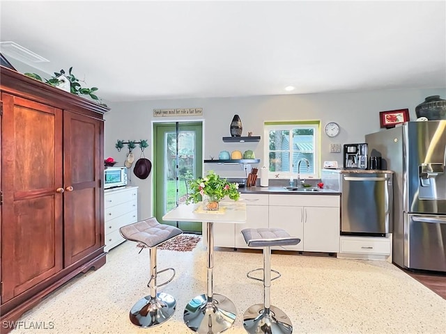 kitchen featuring dark brown cabinets, stainless steel appliances, open shelves, and a sink