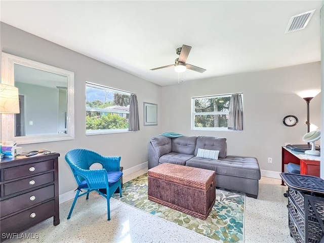living area featuring a wealth of natural light, visible vents, speckled floor, and baseboards