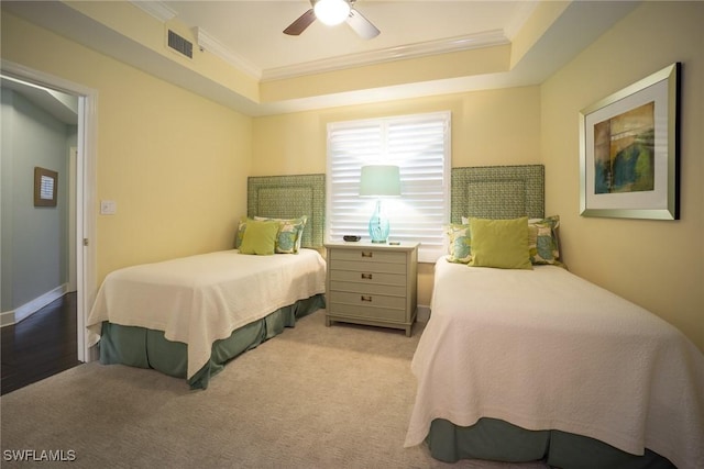 bedroom featuring a raised ceiling, a ceiling fan, visible vents, ornamental molding, and carpet floors
