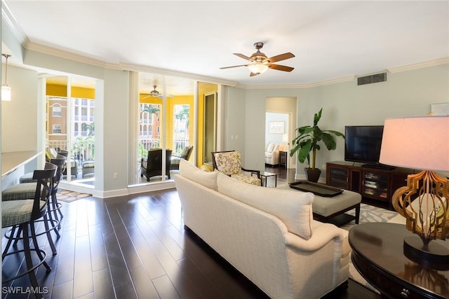 living room with crown molding, visible vents, ceiling fan, and dark wood finished floors
