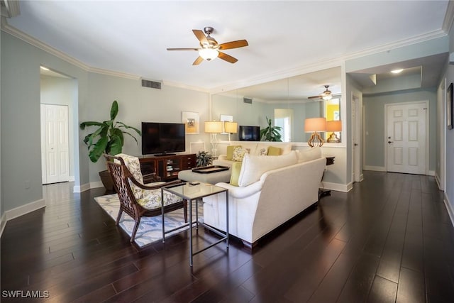 living room with crown molding, visible vents, baseboards, dark wood finished floors, and a ceiling fan