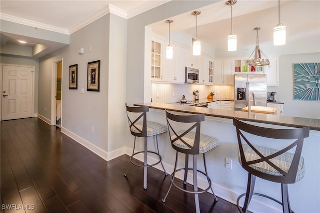 kitchen featuring stainless steel appliances, decorative backsplash, glass insert cabinets, a breakfast bar area, and a peninsula