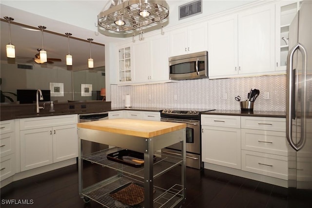 kitchen featuring white cabinets, a sink, appliances with stainless steel finishes, visible vents, and backsplash