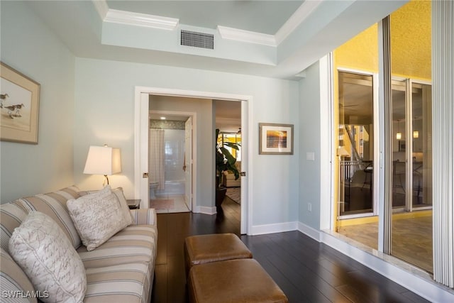living area with dark wood-style flooring, baseboards, visible vents, a raised ceiling, and crown molding
