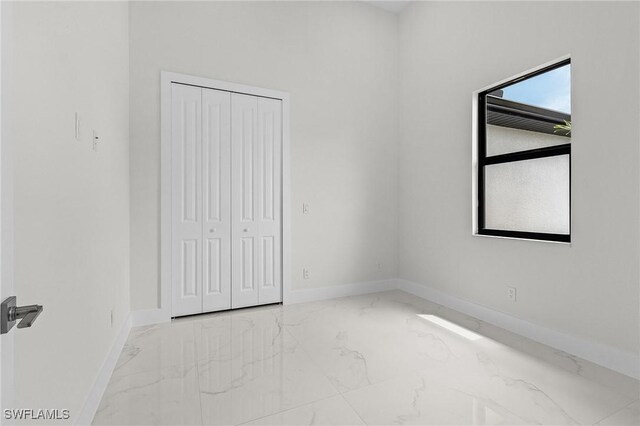 806 Santa Barbara Blvd, Cape Coral, FL 33991 - unfurnished bedroom featuring marble finish floor, a closet, and baseboards