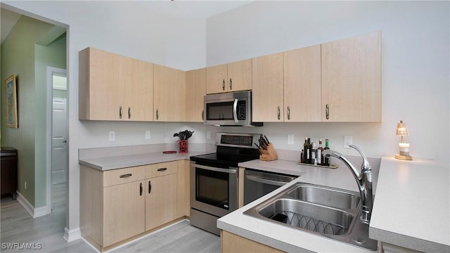 761 Grand Rapids Blvd, Naples, FL 34120 - kitchen with stainless steel appliances, light brown cabinets, a sink, light wood-style flooring, and light countertops