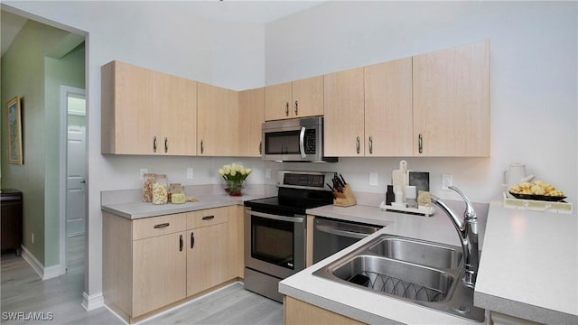 761 Grand Rapids Blvd, Naples, FL 34120 - kitchen featuring appliances with stainless steel finishes, light brown cabinets, a sink, light wood-style flooring, and light countertops