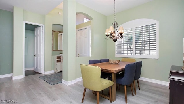 761 Grand Rapids Blvd, Naples, FL 34120 - dining room featuring arched walkways, a chandelier, light wood-type flooring, and plenty of natural light
