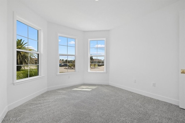 carpeted empty room featuring baseboards