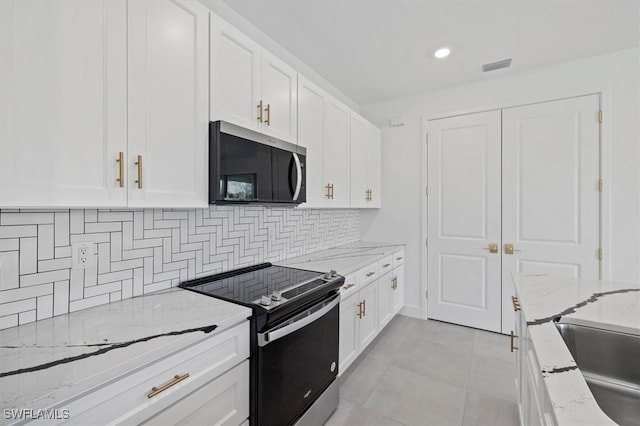 kitchen featuring stainless steel microwave, electric stove, white cabinets, and backsplash