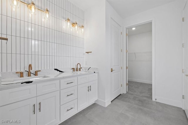 bathroom featuring baseboards, a spacious closet, and a sink