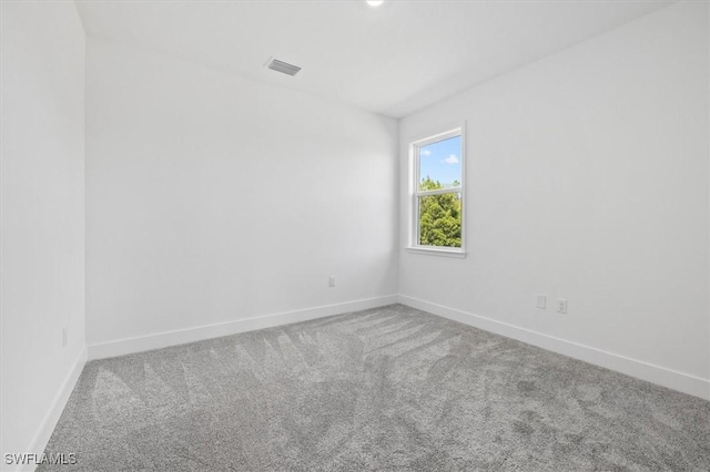 carpeted spare room with visible vents and baseboards