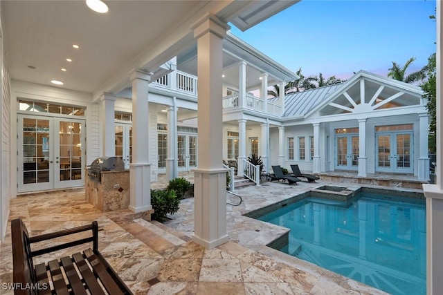 rear view of house featuring an outdoor kitchen, metal roof, french doors, an outdoor pool, and a patio