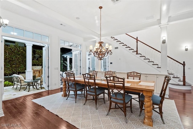 dining room featuring visible vents, decorative columns, stairs, hardwood / wood-style floors, and a notable chandelier