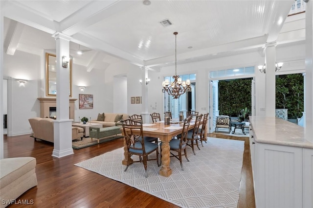 dining area with an inviting chandelier, wood finished floors, ornate columns, beamed ceiling, and visible vents