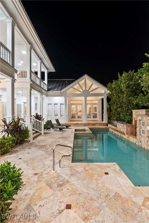 pool at twilight featuring a patio, an outdoor pool, and french doors