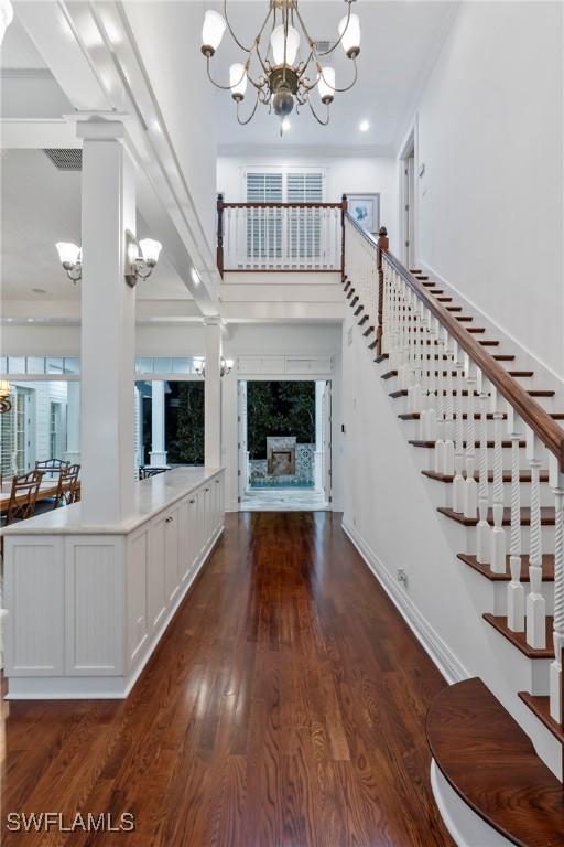 entrance foyer featuring stairway, a notable chandelier, ornate columns, and a premium fireplace
