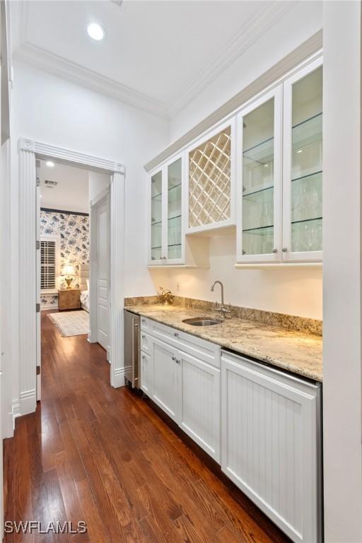 bar featuring a sink, crown molding, indoor wet bar, and dark wood-style floors