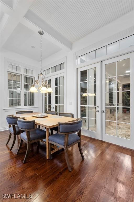 dining space with an inviting chandelier, beamed ceiling, french doors, and dark wood-type flooring