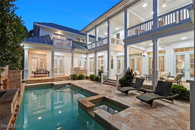 rear view of property with a standing seam roof, a balcony, french doors, a patio, and metal roof