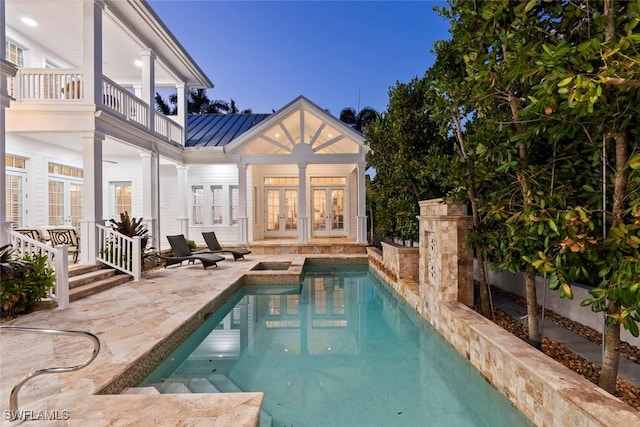 rear view of property featuring a balcony, french doors, a standing seam roof, a patio area, and metal roof