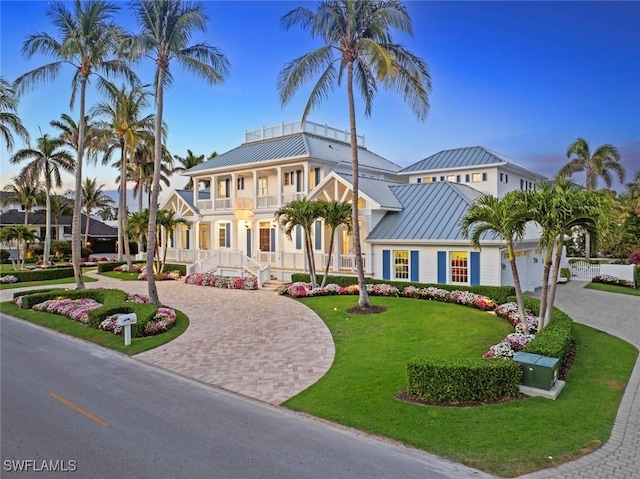 mediterranean / spanish-style home featuring a front yard, a balcony, a standing seam roof, curved driveway, and metal roof