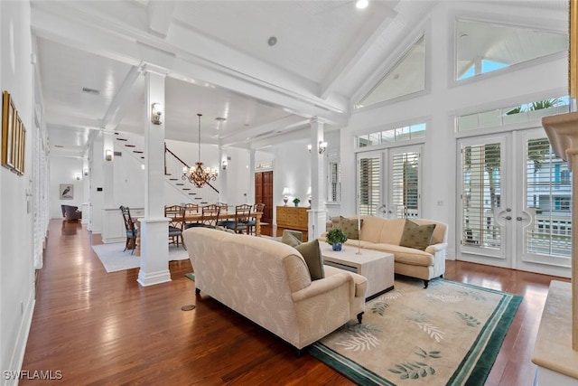 living area featuring decorative columns, wood finished floors, stairway, and beamed ceiling