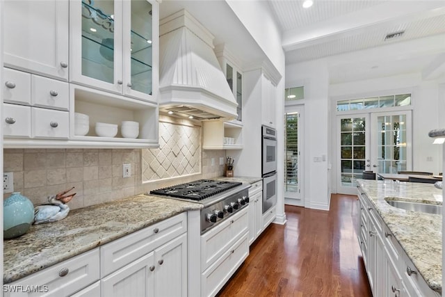 kitchen featuring white cabinets, stainless steel appliances, decorative backsplash, and premium range hood