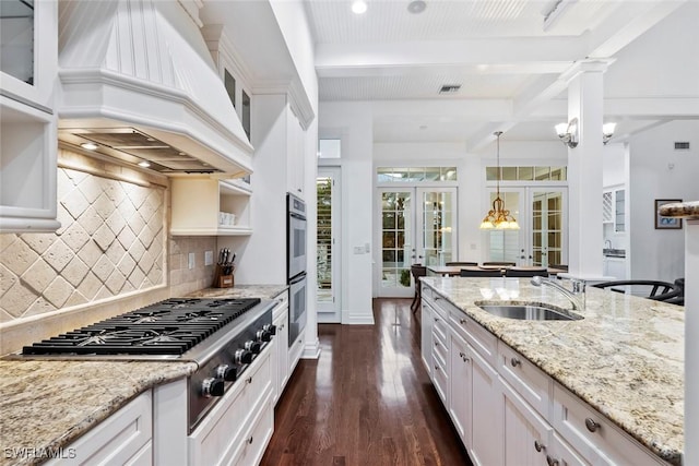 kitchen with appliances with stainless steel finishes, a sink, beam ceiling, french doors, and custom range hood