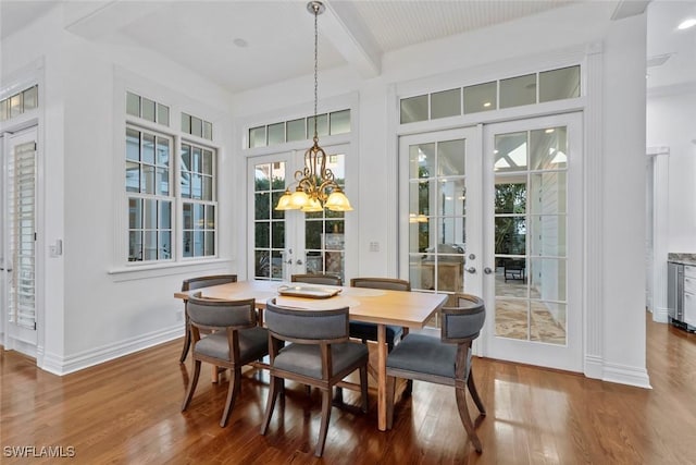 dining space featuring wood finished floors, beam ceiling, baseboards, french doors, and a notable chandelier