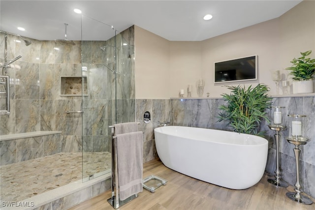 15140 Harbour Isle Dr Unit 502, Fort Myers, FL 33908 - bathroom featuring tile walls, a freestanding tub, a marble finish shower, wood finished floors, and recessed lighting