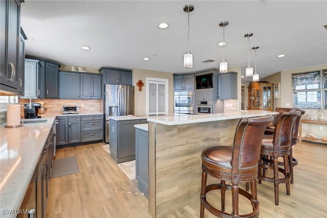 15140 Harbour Isle Dr Unit 502, Fort Myers, FL 33908 - kitchen featuring a kitchen island, appliances with stainless steel finishes, backsplash, light wood-type flooring, and light countertops