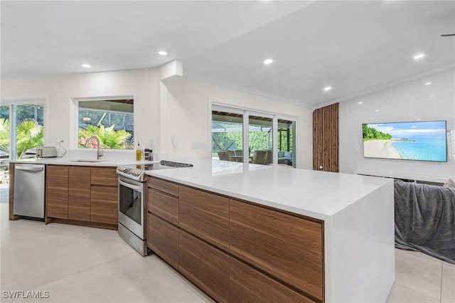 kitchen featuring brown cabinetry, stainless steel appliances, light countertops, a sink, and modern cabinets
