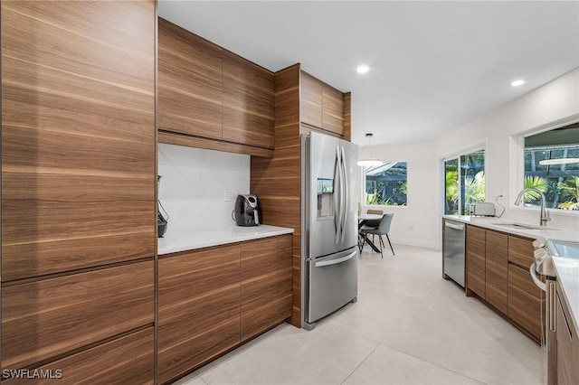 kitchen with appliances with stainless steel finishes, modern cabinets, brown cabinetry, and a sink