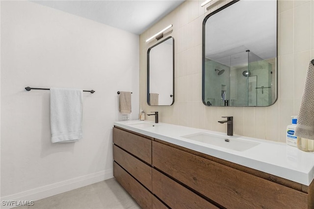 bathroom featuring double vanity, a shower stall, baseboards, and a sink