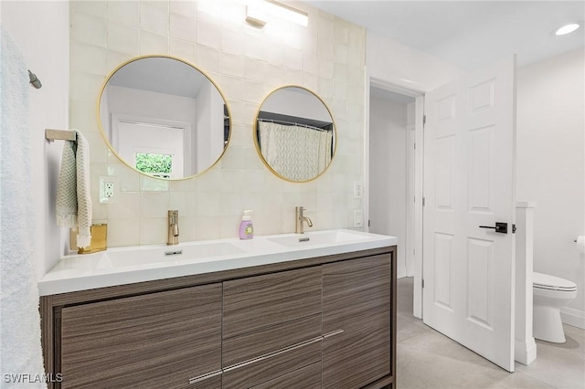 full bathroom with tasteful backsplash, toilet, double vanity, and a sink