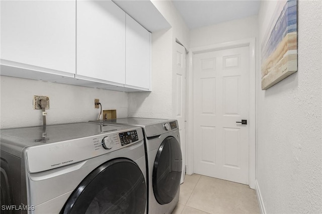 clothes washing area featuring light tile patterned floors, cabinet space, independent washer and dryer, and baseboards