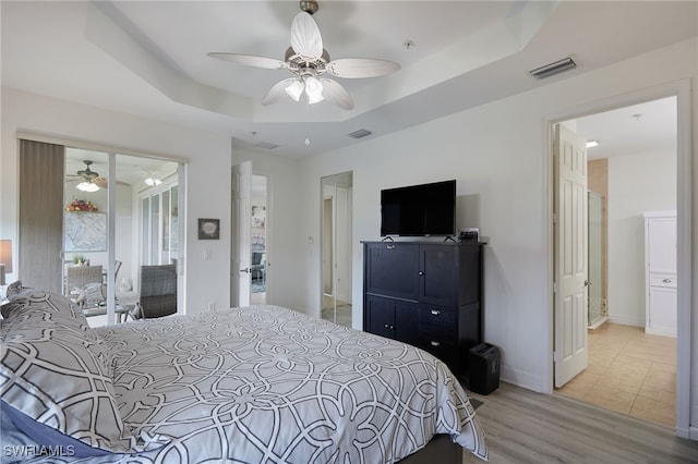 bedroom featuring a raised ceiling, a ceiling fan, light wood-type flooring, and visible vents