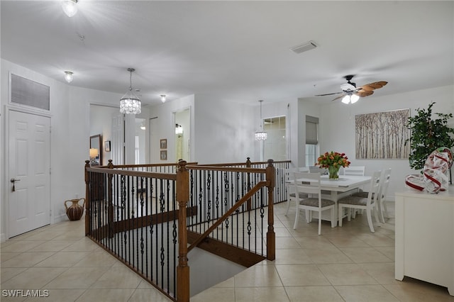 corridor with an inviting chandelier, light tile patterned flooring, an upstairs landing, and visible vents