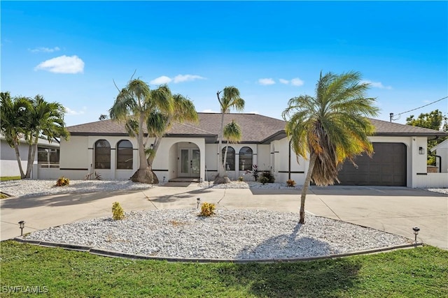 828 SW 51st Ter, Cape Coral, FL 33914 - view of front of property featuring stucco siding, french doors, an attached garage, and curved driveway