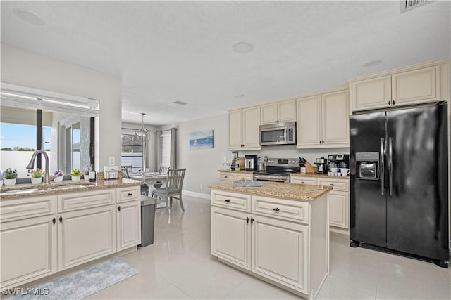 828 SW 51st Ter, Cape Coral, FL 33914 - kitchen with light stone counters, stainless steel appliances, cream cabinetry, a sink, and light tile patterned flooring