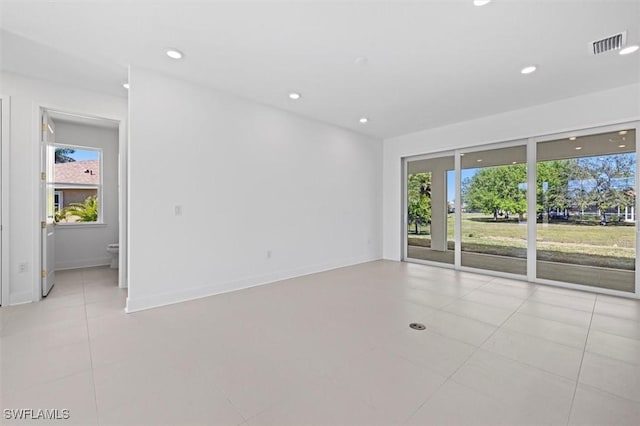 empty room featuring visible vents, light tile patterned floors, and a healthy amount of sunlight