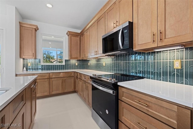 kitchen featuring electric range, light countertops, and stainless steel microwave