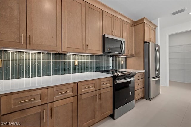 kitchen with tasteful backsplash, visible vents, stainless steel appliances, light countertops, and brown cabinetry