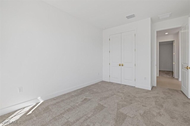 unfurnished bedroom with baseboards, visible vents, a closet, and carpet