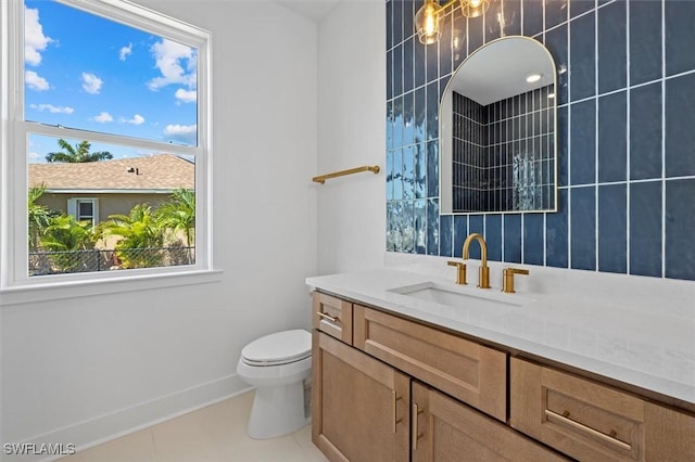 bathroom with baseboards, a healthy amount of sunlight, toilet, and vanity