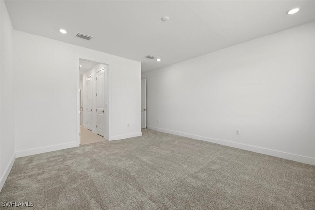 unfurnished room with recessed lighting, visible vents, light carpet, and baseboards