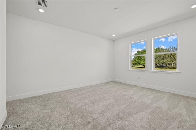 carpeted empty room with baseboards, visible vents, and recessed lighting