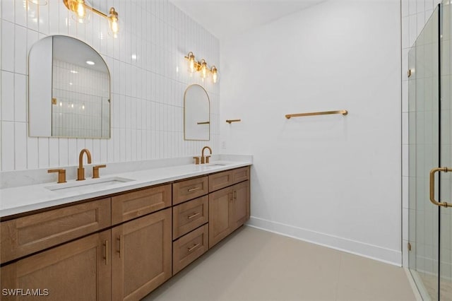 full bath featuring double vanity, a tile shower, baseboards, and a sink