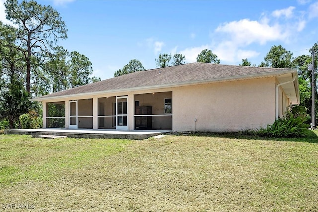 back of house featuring stucco siding, a yard, and a sunroom
